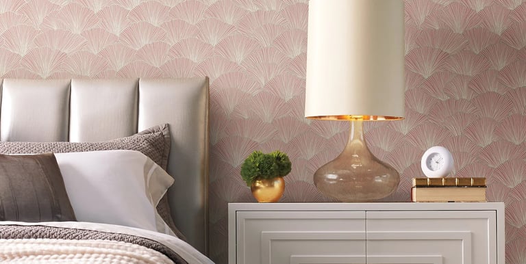 Modern bedroom with pink ginkgo leaf wallpaper, a white nightstand, and a glass table lamp.