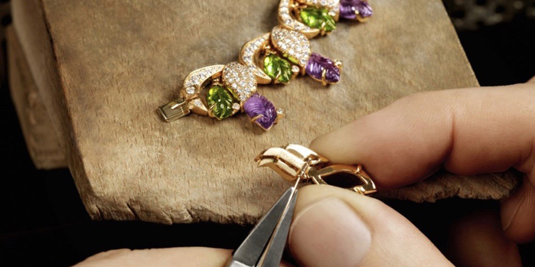 Setting faceted cut amethysts stones into a large 18 karat yellow gold linked necklace.
