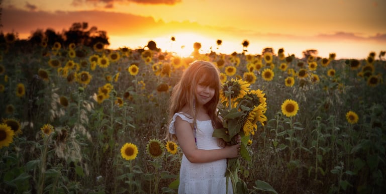 a girl in a white dress holding a bouquet of sunflowers