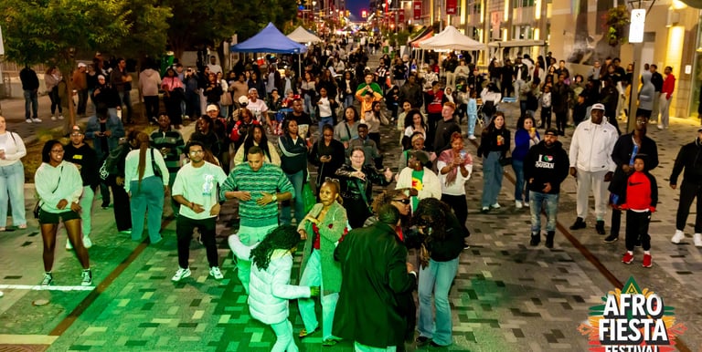 Crowd dancing at the Afro Fiesta Festival street party at night with music and vendors.