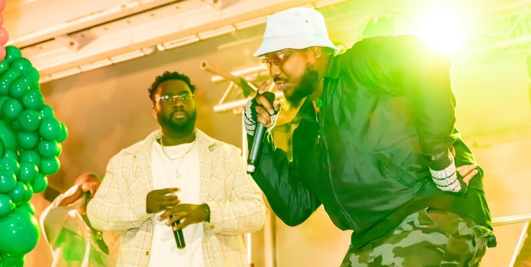 Musician in a white bucket hat and camo pants performing live on stage at Afro Fiesta Festival.