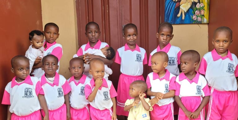 Group of African students in pink and white uniforms posing for a school photo together.