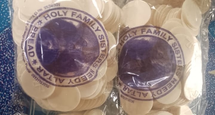 Stacks of white communion wafers altar bread in bags from Holy Family Sisters.