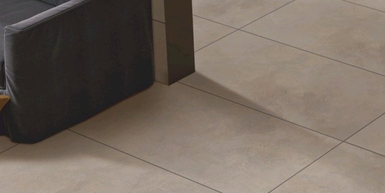 Manrise Enterprises- Modern interior with large beige tile flooring and a dark grey sofa.