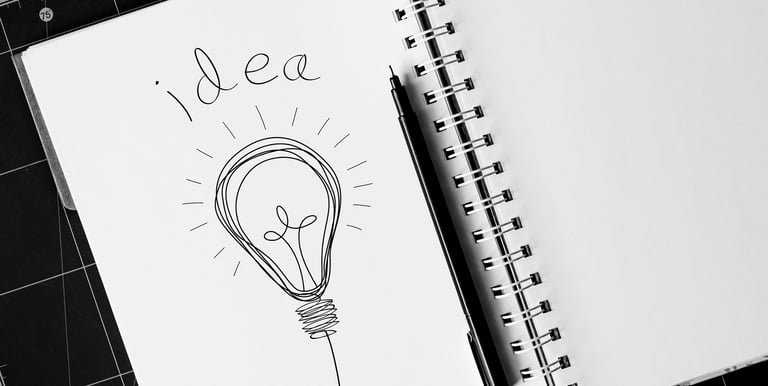 Hand-drawn light bulb sketch with the word idea in a spiral notebook, symbolizing creative brainstorming.