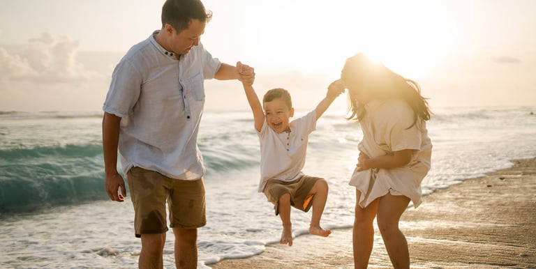 Father lifting child during sunset family session at Melasti Beach Bali, candid emotional moment
