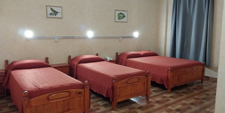 Una habitación con tres camas y un ventilador de techo.