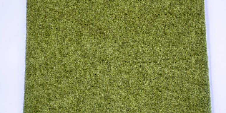 Dark green yak wolle shawl neatly folded on white background, showing soft wool texture and edges.