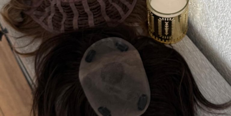 Toppers capillaires bruns posés sur une table à côté d’un photophore doré.