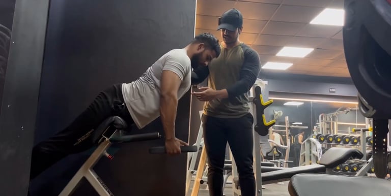 A focused coach teaching his client how to perform hyperextension exercise