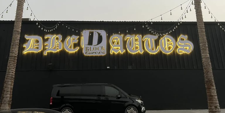 Back Light DBE Autos sign mounted on wall