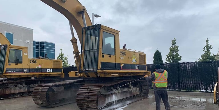 Caterpillar excavator at a construction site being pressure washed