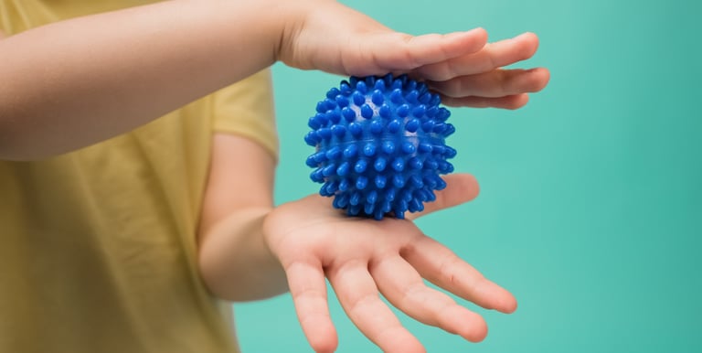 a child's hand holding a blue ball