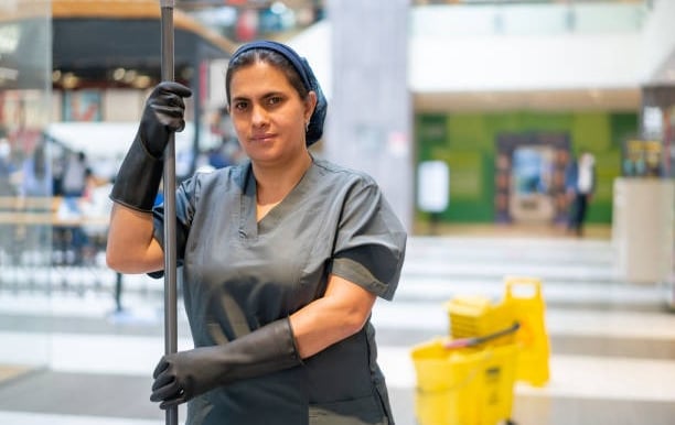 a woman in a black dress and gloves holding a mop