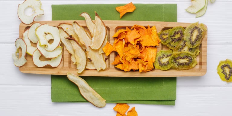 Tabla de picada con manzana, pera, mango y kiwi deshidratados en rodajas.