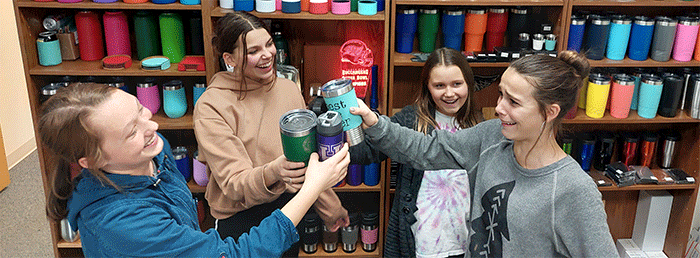 a group of people standing around a table holding tumblers