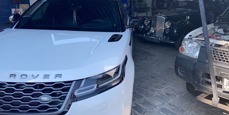 a white car parked in a garage with a man standing next to it
