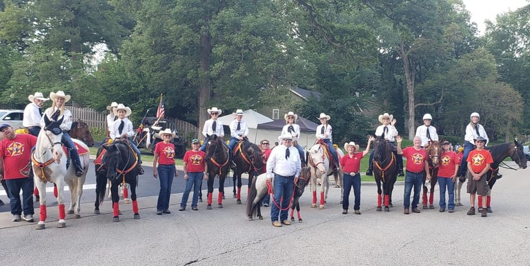 A group of people on and off horses waiting for a parade to start.