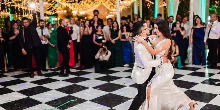 Una pareja de recién casados ​​compartiendo su primer baile en una pista de baile a cuadros.