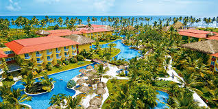 Aerial view of a luxury beachfront tropical resort with blue swimming pools and palm trees.