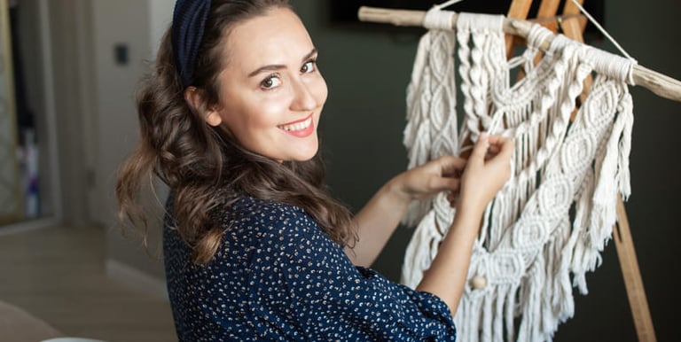 Mujer sonriente creando un exclusivo tapiz decorativo de macramé hecho a mano, dando vida a piezas ú