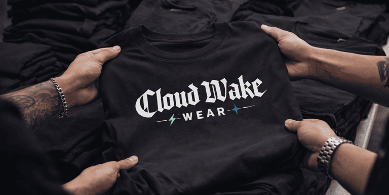 Manos sosteniendo una playera de la marca Cloud Wake Wear