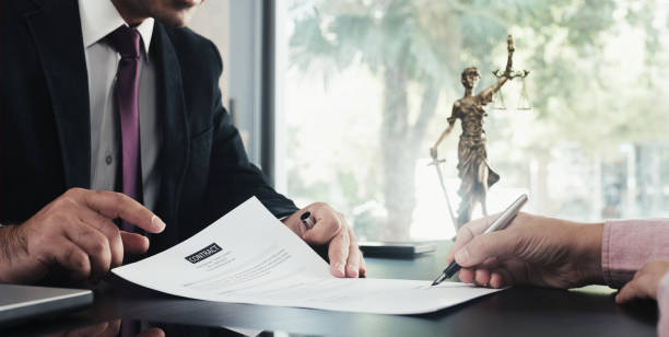 signature d'un papier par un client avec son avocat avec stylo à encre, statue justice à l'arrière 