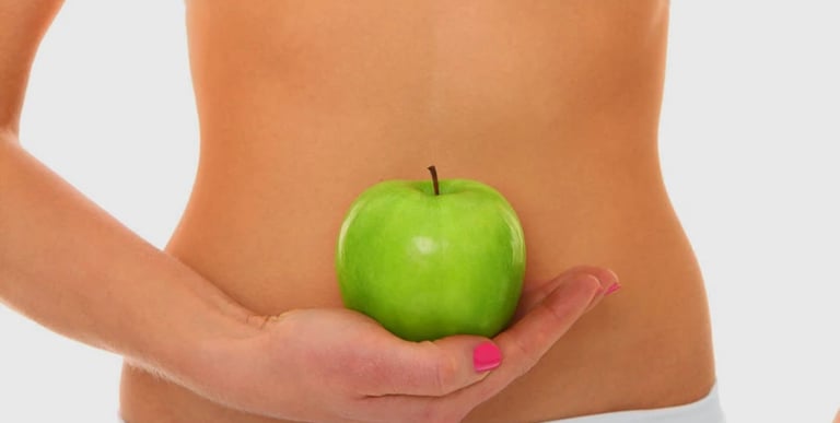 Person holding a green apple at the abdomen, symbolising Chi Nei Tsang focus on digestive organ health and energy flow