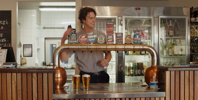 a man is standing behind a bar with beer