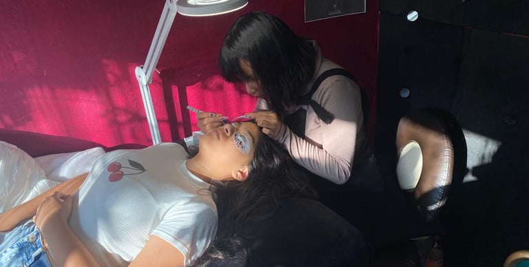Artista profesional de pestañas aplicando extensiones de pestañas individuales a una clienta