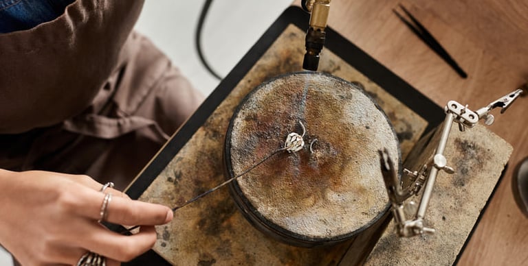 Joyera utilizando un soplete de soldadura en un anillo de plata en un banco de trabajo profesional.