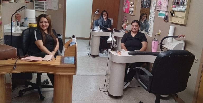 Student nail technicians sitting at individual manicure stations in a college beauty salon.