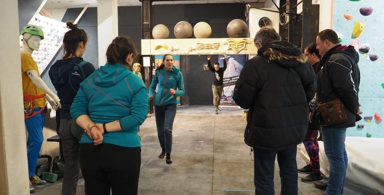 a group of people standing around a climbing wall