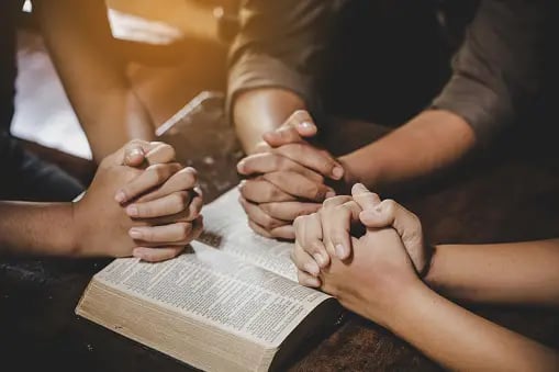a group of people holding hands over a book