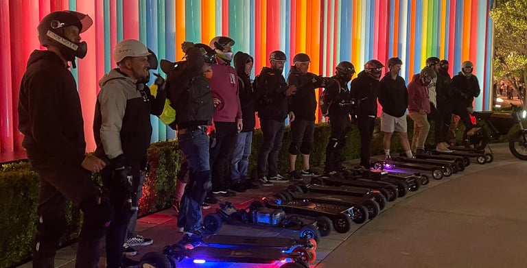 a group of people standing around a group of electric skateboards