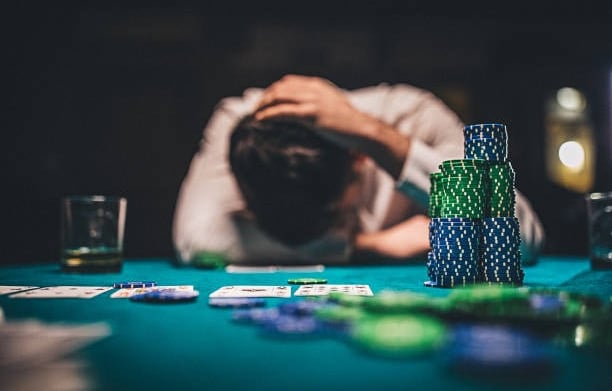 a man is sitting at a table with poker chips and playing cards