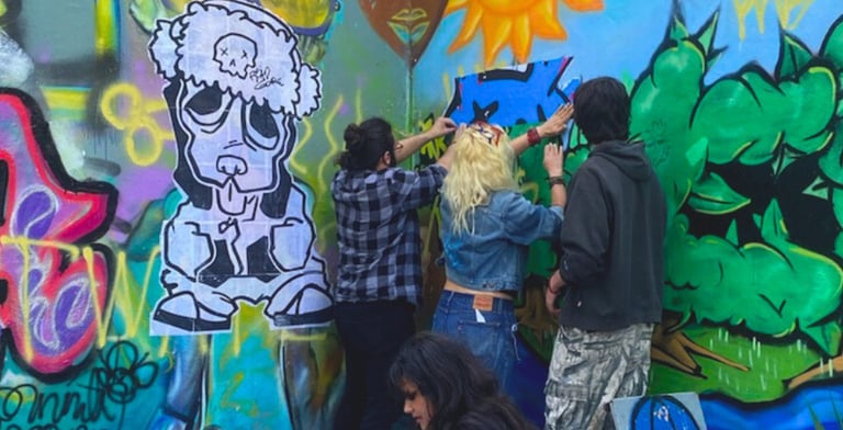 artist leading young people installing a wheat paste mural