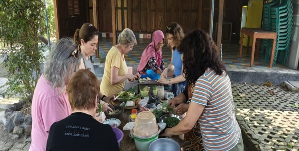 a group of people standing around a table with food