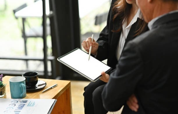 a man and woman sitting at a table with a tablet