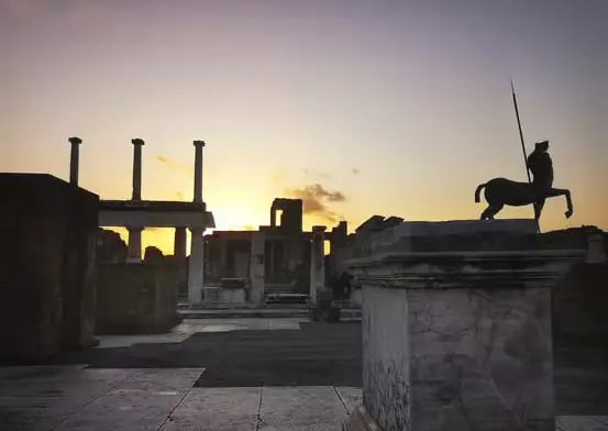 Silhouette of centaur statue at Pompeii Forum during golden sunset, ancient columns