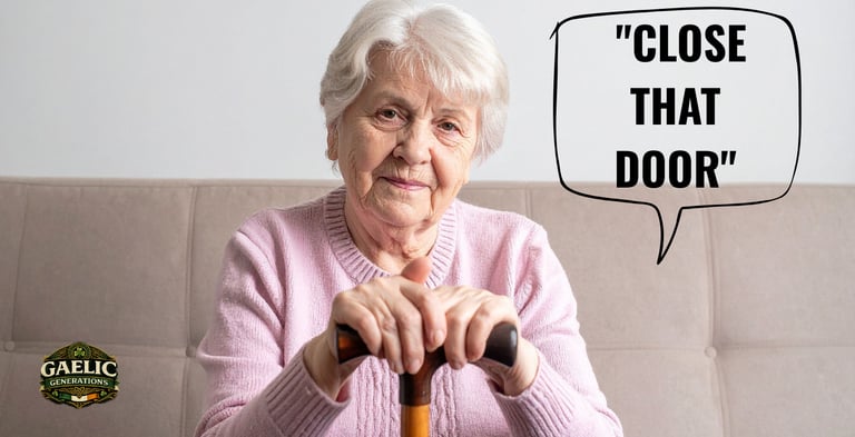 An elderly Irish woman with a walking stick sitting on a couch with "Close That Door" speech bubble