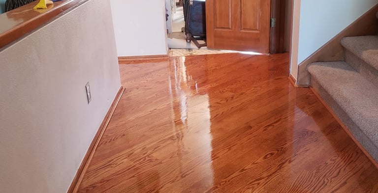 Polished red oak hardwood flooring with a high-gloss finish in a home entryway and hallway.