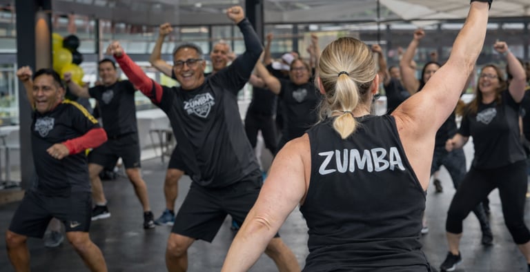 Adultos activos participando en una clase de Zumba fitness en interiores