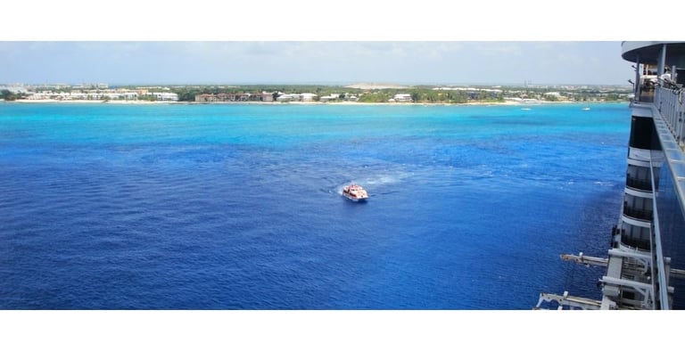 Navio de cruzeiro chegando a George Town, Grand Cayman, com o mar azul-turquesa cristalino ao fundo.