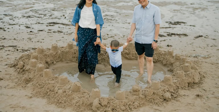 Family walking barefoot across the sand during a natural family photography session at Nusa Dua Beach Bali