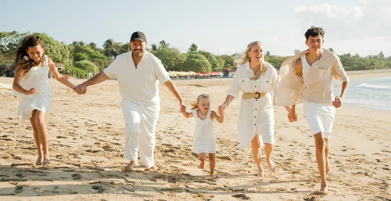 Family running together on the beach during golden hour at Ayodya Resort Bali in Nusa Dua