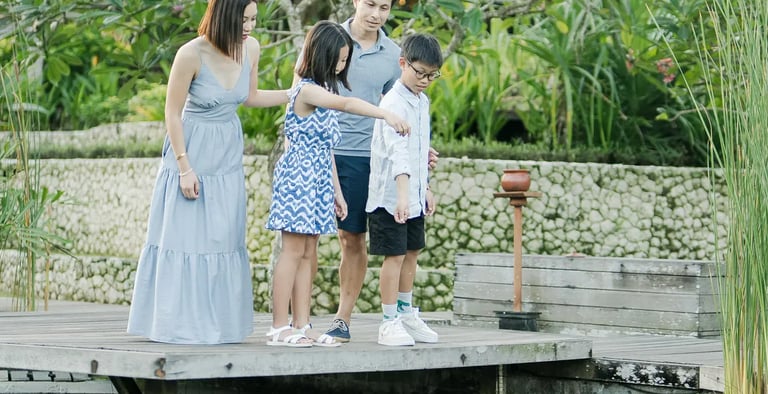 Family enjoying time together in a tropical garden during a luxury family photography session at The Ritz-Carlton Bali.