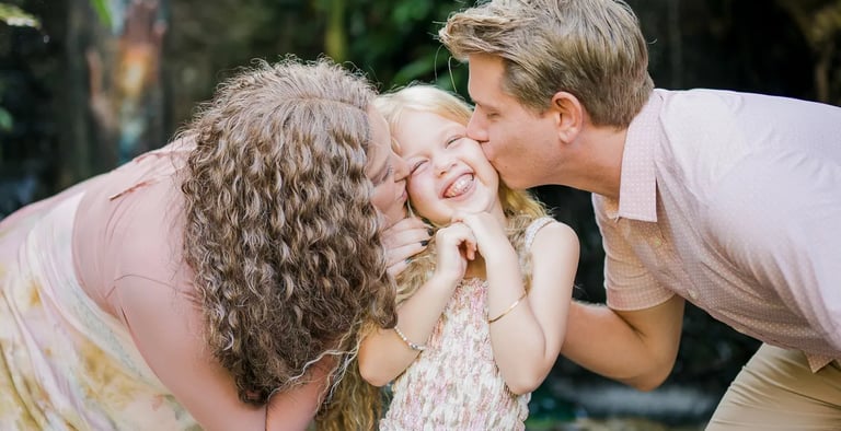 Parents kissing their daughter during a natural family photography session in Ubud Bali