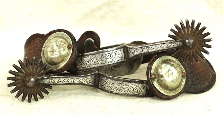 Vintage Western spurs with intricate silver detailing.