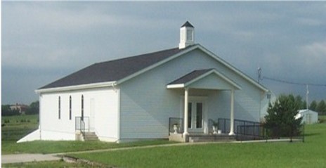 Basehor Church of Christ is a white church building with a black roof that has a covered porch.